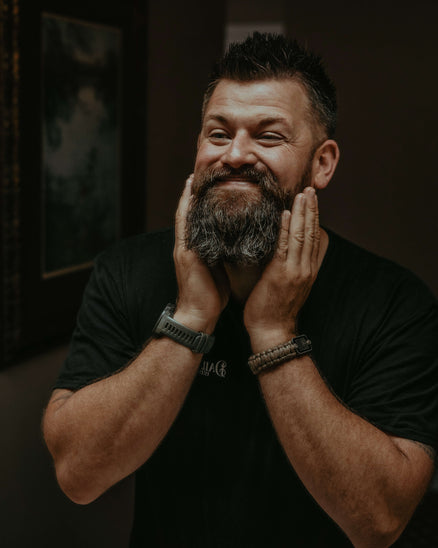 man looking at beard growth in mirror and touching beard