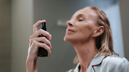 Woman spraying toner on face