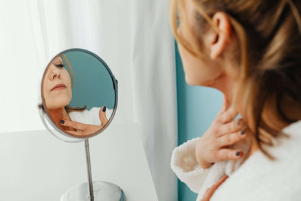 woman looking in mirror at skin