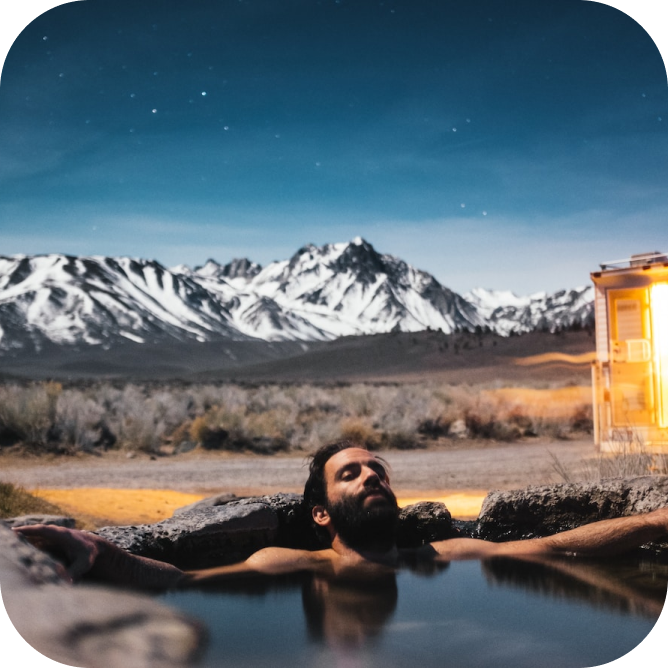Man in outdoor bath with mountains in background