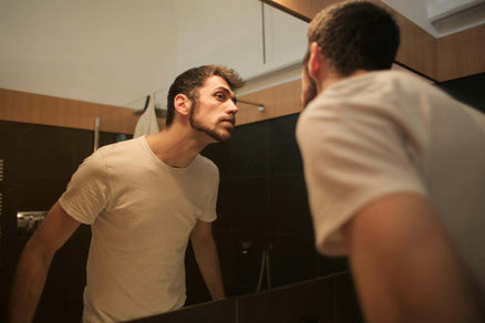 Man looking at beard in the mirror before bed