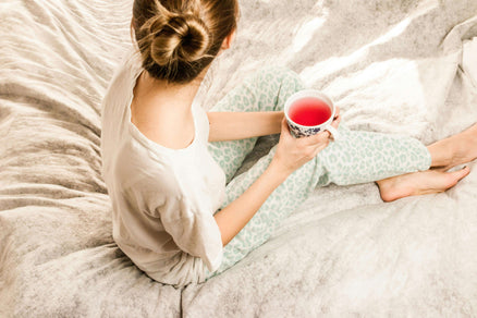 woman in pajamas in bed with tea for a self-care night