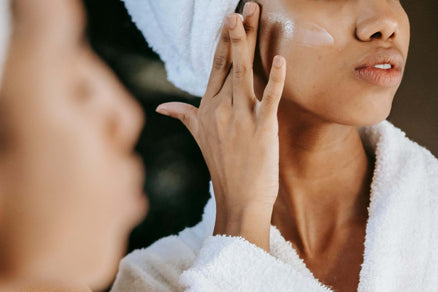 Woman applying moisturizer to face for skincare